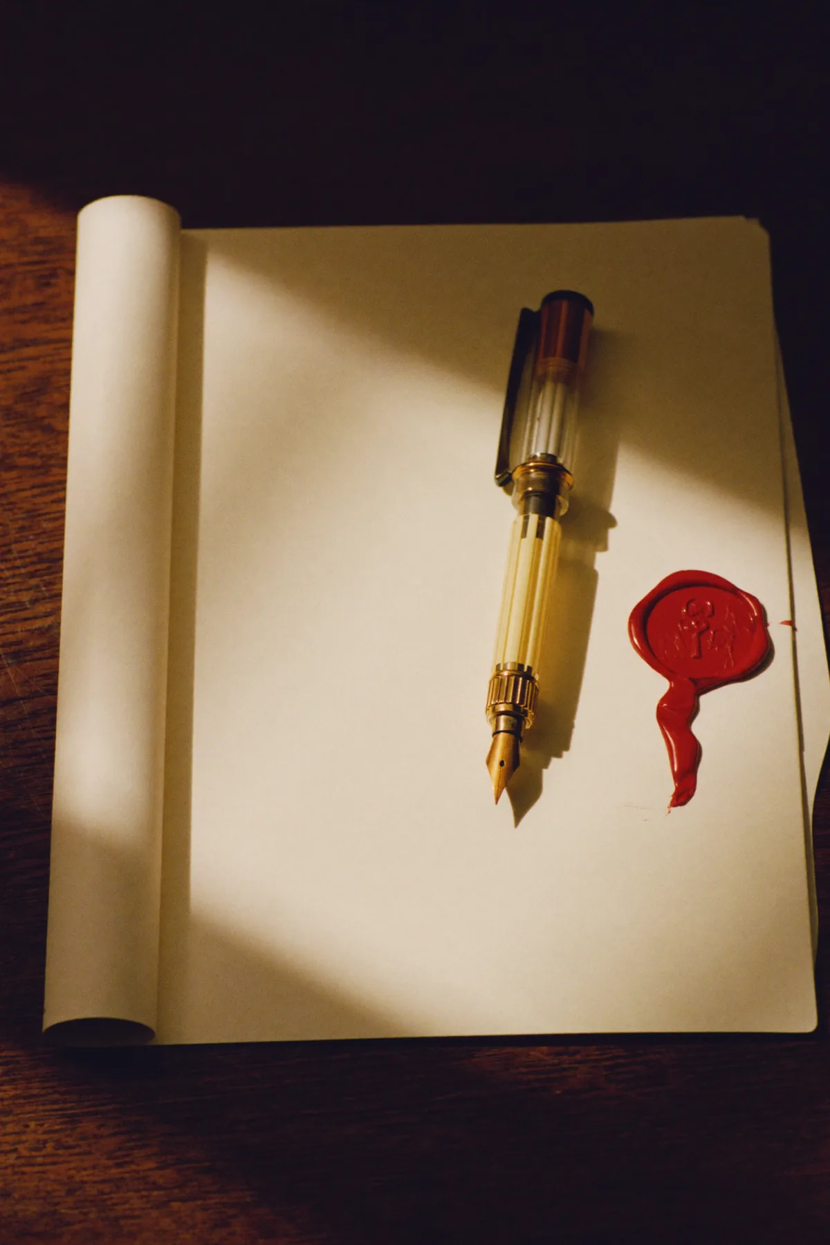 A fountain pen beside a red wax seal on blank paper